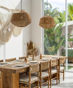 une salle à manger avec une table en bois et des chaises en rotin dans l'établissement Matanai Villas, à Canggu