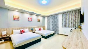 um quarto de hotel com duas camas e uma televisão em 澎湖凱悅輕旅電梯民宿 em Magong