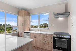 uma cozinha com um lavatório e duas janelas em Sun and Coast - Mangawhai Heads Holiday Home em Mangawhai