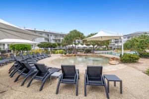 a group of chairs sitting around a swimming pool at Resort on the Beach Dual Unit 5203 in Kingscliff