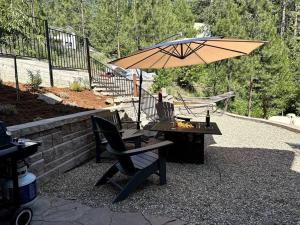 a patio with a table and a chair and an umbrella at Timberwood Cottage in Downtown Twain Harte in Twain Harte