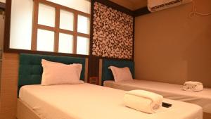 SonāmuraにあるHotel Maisha Internationalのベッド2台と窓が備わる客室です。