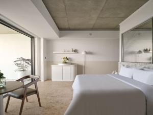a white bedroom with a bed and a table and a chair at Ardo in Townsville