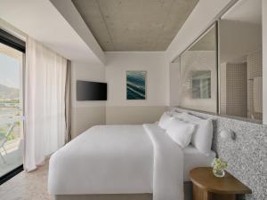 a white bedroom with a large bed and a window at Ardo in Townsville
