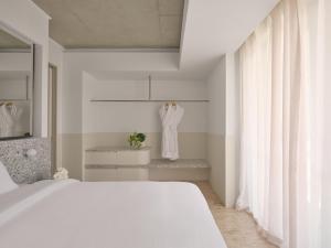 a white bedroom with a bed and a mirror at Ardo in Townsville