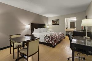 a hotel room with a bed and a table and chairs at Red Roof Inn & Suites Cave City in Cave City
