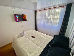 Schlafzimmer mit einem Bett mit Fernbedienung in der Unterkunft EmbajadaUsacorferiasAeropuertoG12Agora in Bogotá