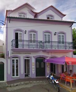 une maison violette avec des personnes assises sous un parapluie dans l'établissement Apartment in Biscoitos Terceira, à Biscoitos