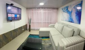 sala de estar con sofá blanco y TV de pantalla plana en EmbajadaUsacorferiasAeropuertoG12Agora en Bogotá