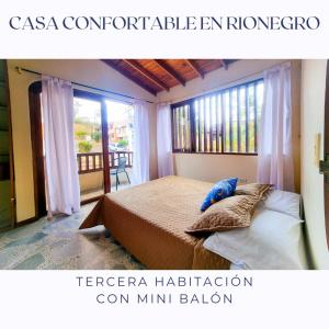 um quarto com uma cama e uma grande janela em Casa Confortable en Rionegro - a 10 min del aeropuerto em Rionegro
