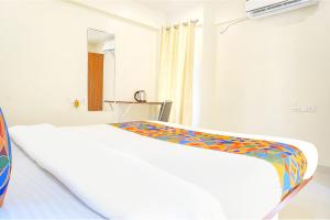 ein Schlafzimmer mit einem weißen Bett mit einer bunten Decke in der Unterkunft FabHotel Majestic Luxurious in Pune
