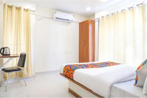 een slaapkamer met een bed, een bureau en een stoel bij FabHotel Majestic Luxurious in Pune