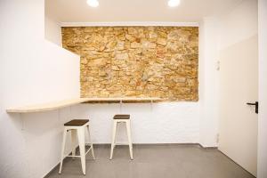 a room with two stools and a stone wall at Hotel Casa Mas in Lloret de Mar