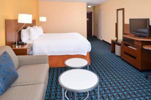 a hotel room with a bed and a couch and a tv at Fairfield Inn Orlando Airport in Orlando