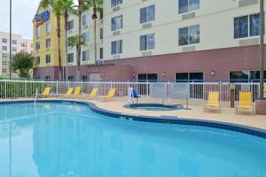 uma piscina com cadeiras e um edifício em Fairfield Inn Orlando Airport em Orlando
