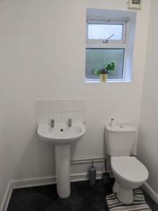 a bathroom with a toilet and a sink and a window at Double Rooms with shared bathroom in Gillingham