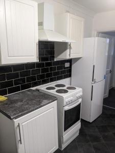 a white kitchen with a stove and a refrigerator at Double Rooms with shared bathroom in Gillingham