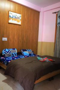 a bedroom with a large bed with a wooden wall at OTW Guest House & Mountain Cafe in Kasol