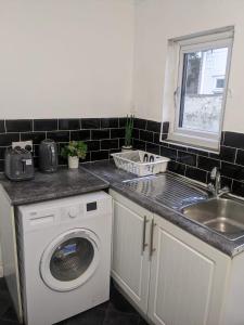 uma cozinha com uma máquina de lavar roupa e um lavatório em Contractors Accommodation in Gillingham - Ideal for long and short stay em Gillingham