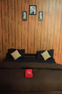 ein Bett mit zwei Kissen und einem roten Hut darauf in der Unterkunft OTW Guest House & Mountain Cafe in Kasol