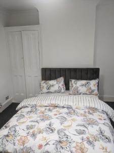 a bedroom with a bed with a floral comforter and pillows at Double Rooms with shared bathroom in Gillingham