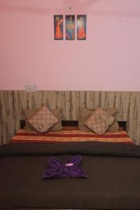 una cama con un moño púrpura encima en OTW Guest House & Mountain Cafe, en Kasol
