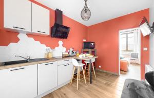 een keuken met oranje muren en een tafel met krukken bij 1 Bedroom Cozy Apartment In Melrand in Melrand