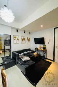 a living room with a black leather couch and a tv at Azure Urban Resort near NAIA Airport in Manila