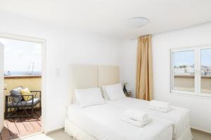 a white bedroom with a bed and a window at Penthouse with Panoramic View by FeelHome in Tel Aviv