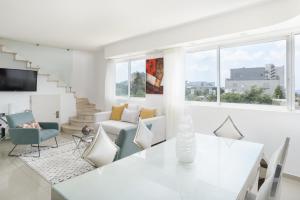 uma sala de estar branca com uma mesa e cadeiras em Penthouse with Panoramic View by FeelHome em Tel Aviv