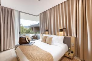 a bedroom with a white bed and a window with curtains at Twinpalms MontAzure in Kamala Beach