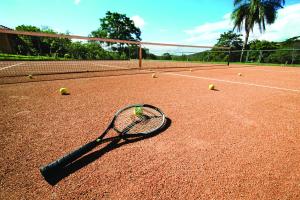 racchetta da tennis e palline da tennis su un campo da tennis di Rancho Cipo Pousada a Serra do Cipo