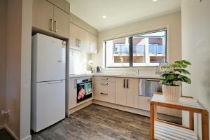 a kitchen with a white refrigerator and a window at Two-Bedroom House with Jacuzzi at Rototuna! in Hamilton