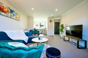 a living room with a blue couch and a tv at Two-Bedroom House with Jacuzzi at Rototuna! in Hamilton