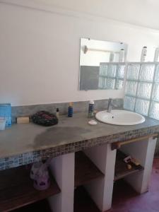 eine Badezimmertheke mit einem Waschbecken und einem Spiegel in der Unterkunft Maison jaune bord de la mer in Ambatoloaka