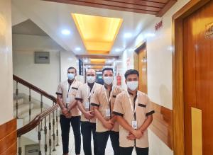 a group of men standing in a hallway wearing masks at Hotel Shahin(residential) in Dhaka