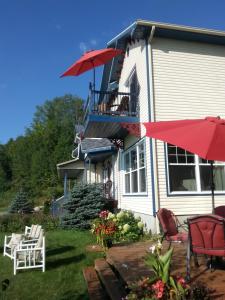 a house with chairs and umbrellas in the yard at Domaine de la Baie, Les Suites in Shawinigan