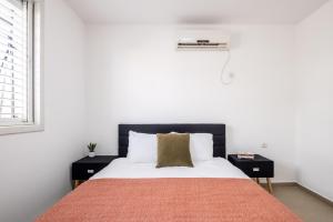 a bedroom with a bed with white walls and a window at Poleg Serenity Villa by Sea N' Rent in Netanya