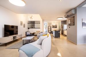 a living room with a white couch and a tv at Poleg Serenity Villa by Sea N' Rent in Netanya