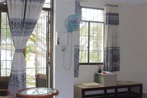 a room with windows and a table and a fan at Bụi Hostel - Bến Tàu Rạch Giá in Rạch Giá