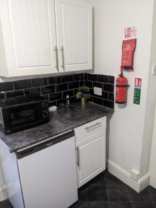 a kitchen with white cabinets and a microwave at Double Rooms with shared bathroom in Gillingham