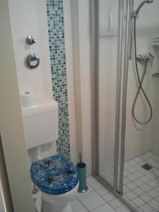 a bathroom with a shower and a toilet with a blue seat at Apartment Kleiner Heinrich in Braunlage