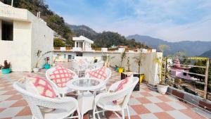 eine Terrasse mit weißen Stühlen und einem Tisch auf dem Dach in der Unterkunft B2L Hills At Tapoavn in Rishikesh