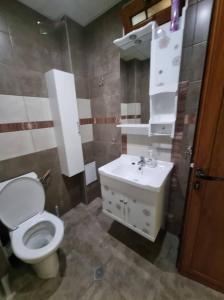 a bathroom with a white toilet and a sink at Апартамент Плевен in Pleven +4 photos