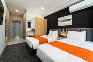 Cette chambre d'hôtel comprend 2 lits avec des draps orange et blancs. dans l'établissement Nuovo Boutique Hotel, à Tachkent