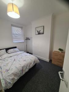 a bedroom with a bed and a dresser in it at Double Rooms with shared bathroom in Gillingham