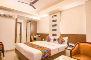 Habitación de hotel con cama y silla en FabHotel Emerald, en Ranchi