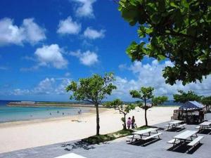 uma praia com um grupo de mesas de piquenique e o oceano em HOTEL StoRK Naha Shintoshin - Vacation STAY 27632v em Naha