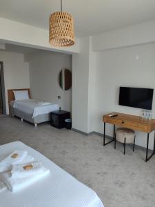 een kamer met 2 bedden, een bureau en een televisie bij Thalassa Hotel Bozcaada in Bozcaada