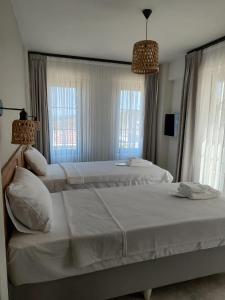 twee bedden in een slaapkamer met twee ramen bij Thalassa Hotel Bozcaada in Bozcaada